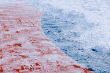 Freshly cleared path reveals vibrant orange and icy blue hues in winter scenery at a frozen park