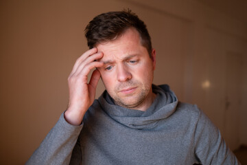 Stressed male having a terrible headache or migraine pain, touching temple.