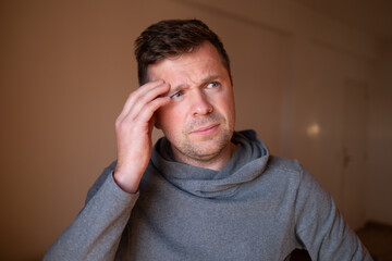 Stressed male having a terrible headache or migraine pain, touching temple.