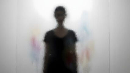 A person stands in front of a blurred background with colorful abstract shapes, depicted in a photographic image from a frontal viewpoint.