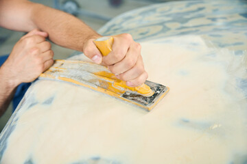 Man polishing car while preparing automobile for painting in workshop