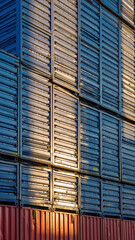 stacked shipping containers reflecting sunlight, forming a geometric pattern.