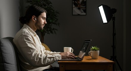 Focused Young Man Working Late on Laptop, Dramatic Lighting, Cozy Home Office