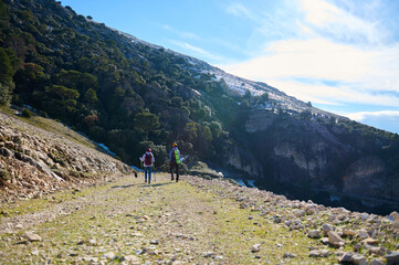 Obraz premium Two Hikers Walking On Rocky Mountain Trail Under Clear Blue Sky
