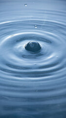 water droplet creating ripples on a calm water surface.