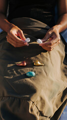 Person holding wireless earbuds with additional earbuds placed on lap.