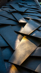Close-up of overlapping dark metal sheets with reflective surfaces.