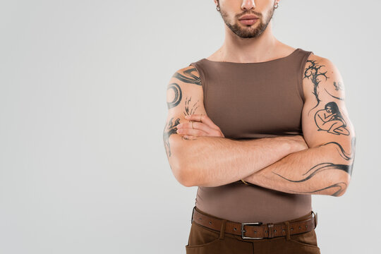 Stylish man showcases tattoos with confidence in minimalistic studio setting