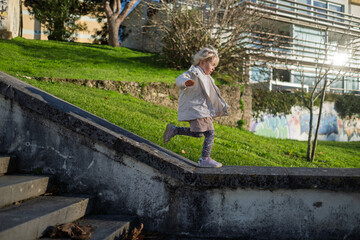 Brave preschool child playing on a low wall in the city, childhood freedom and balance concept.