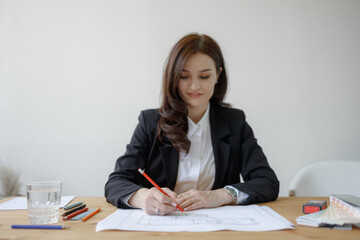 Woman draws on paper at a wooden table in a simple office during daytime