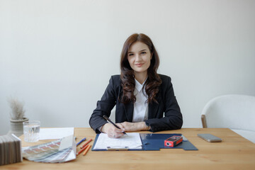 Young woman in business attire working at a desk with documents and office supplies during daytime