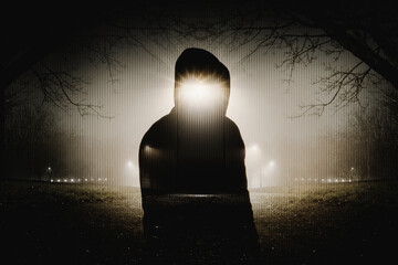 A horror edit of a double expsoure of a ghost like figure. in a park. On a spooky foggy winters night