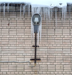 A streetlight on a brick wall surrounded by icicles