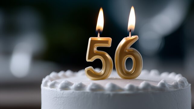 56th birthday cake with gold number 56 candles burning on white buttercream frosting with soft bokeh background