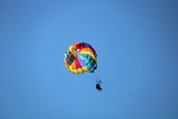 Multicolored paragliding flight in the blue sky. Parasailing