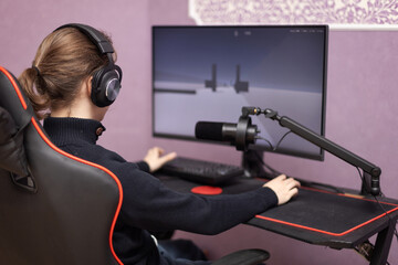 Man with headphones playing video games on modern computer at table indoors,
