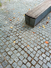 Banco de madera en diagonal con el suelo de adoquines