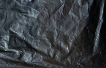 Monochrome wrinkled plastic sheet texture with soft reflections, chaotic folds, and urban grunge abstract background.