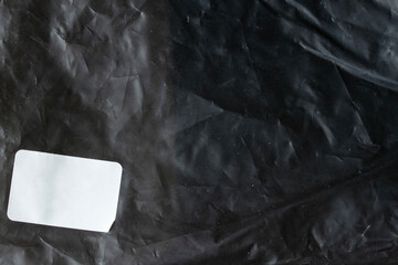 Black wrinkled paper background with clean white blank card for branding mockup and design presentation.