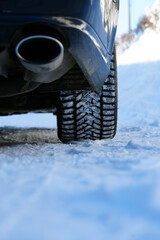 Close-up of car winter tire with snow on a frozen road