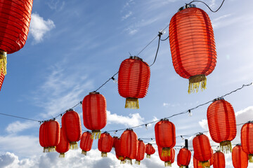Red paper lanterns hanging on garlands against blue sky. Traditional festive street decoration for Chinese New Year celebration. © Anastasiia