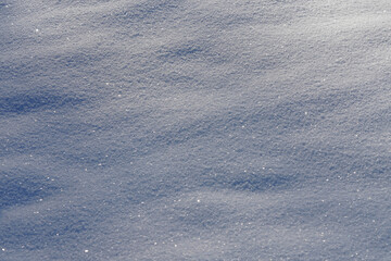 Wide shot of fresh sparkling snow texture with soft drifts in sunlight