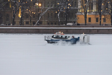 Evening hovercraft drifts over snowcovered river in silence