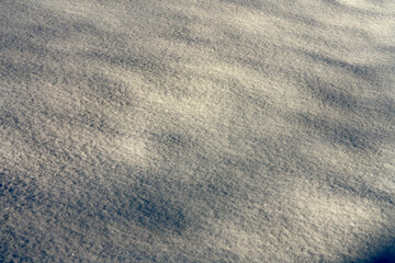 Wide shot of fresh sparkling snow texture with soft drifts in sunlight