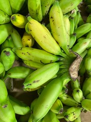 Close up shot of fresh green bananas hanging for sale at a traditional market. Selective focus.