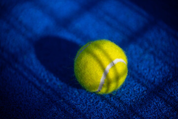 Padel ball on blue court during sunny day, clean and minimalistic image for sports websites, blogs,...