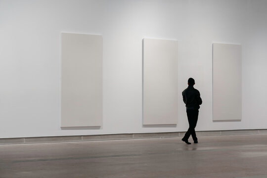 A man is looking at paintings in an art gallery.