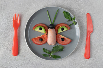 Butterfly made from sausage, tomato, avocado, and olives is healthy breakfast idea for kids