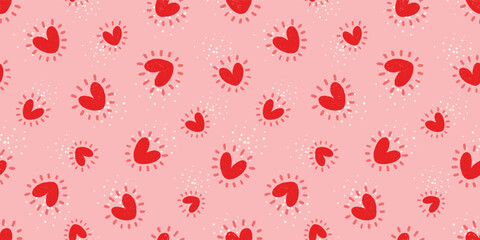 Seamless vector pattern with hand-drawn, textured red hearts surrounded by playful sunburst rays and tiny white dots on pink background for Valentine's Day themes, greeting cards, nursery textiles.