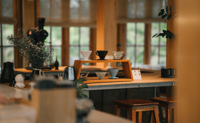 A cozy, minimalist coffee shop featuring a dedicated pour-over station with various ceramic drippers on a wooden stand.