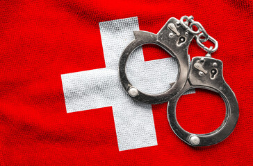 Flag of Switzerland and police handcuffs. Crime and offenses in country Concept
