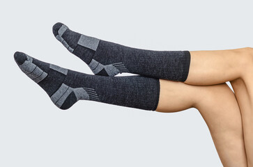 Black long socks on female legs, side view, for design, branding, pattern. Gray background, isolated.
