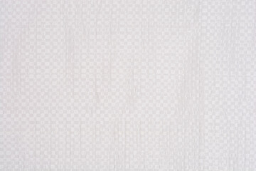A full frame shot of a white woven plastic surface with a repetitive square pattern creating a clean synthetic textile background