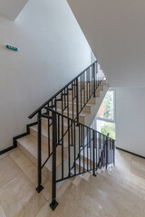 Modern stair case between floors. Stairs with metallic rail in modern building. Interior of a contemporary apartment or office building. Architecture and real estate background.