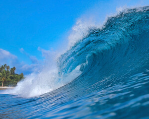Crashing Ocean Wave Curling In Blue, Massive Barrel With White Foam Spray, Glassy Surface Reflecting Sunlight,