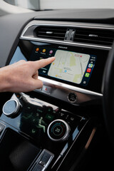 Naklejka premium Hand using Apple CarPlay touchscreen inside modern car