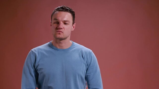 Upset man reacting with sadness on brown background. Concept of emotional intelligence training, recognizing frustration signals, communication breakdown examples, and behavior analysis lessons.