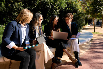 Businesswomen meeting outdoors collaborating using digital devices