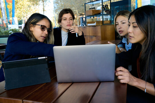 Diverse women collaborating on laptop in cafe - Powered by Adobe