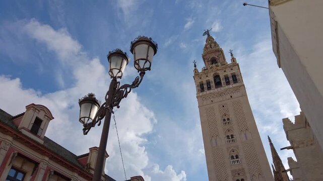 Imposing shape of the Giralda, the famous bell tower of Seville Cathedral, with a streetlight in the foreground