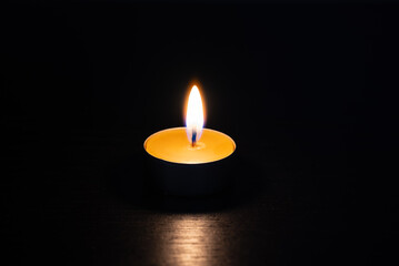 Burning candle in the dark - symbol of hope, safety, care and remembrance. Concept of protection, warmth, spirituality, grief, faith and inner peace.