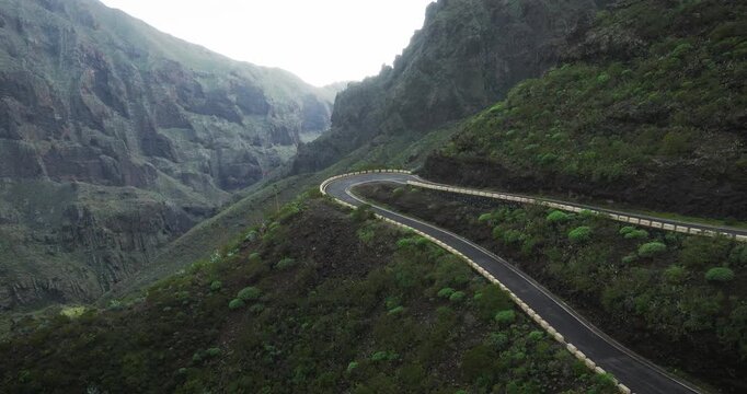 Winding mountain road through a lush green canyon with dramatic rock formations