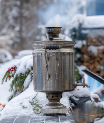 A silver tea kettle sits on a snowy surface