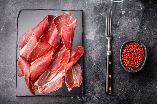 Sliced prsut prshut, Balkan cured pork meat ham. black background. top view