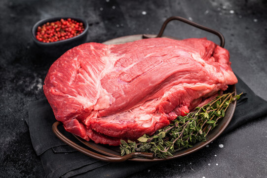 Raw Top Round beef meat cut, topside with hrebs for roast. black background. Top view