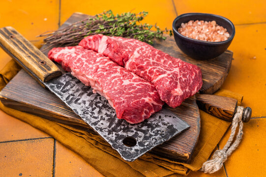 Fresh raw Denver steak, showcasing its marbled texture and rich color, perfect for grilling or pan-searing to create a flavorful meal. orange background. top view